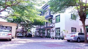 A multi-story building with balconies, parked cars, and potted plants. - Meros Villa Apartment (Lagos)