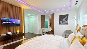 A modern hotel room with a large bed, a desk, a TV, and a mirror. - Meros Villa Apartment (Lagos)