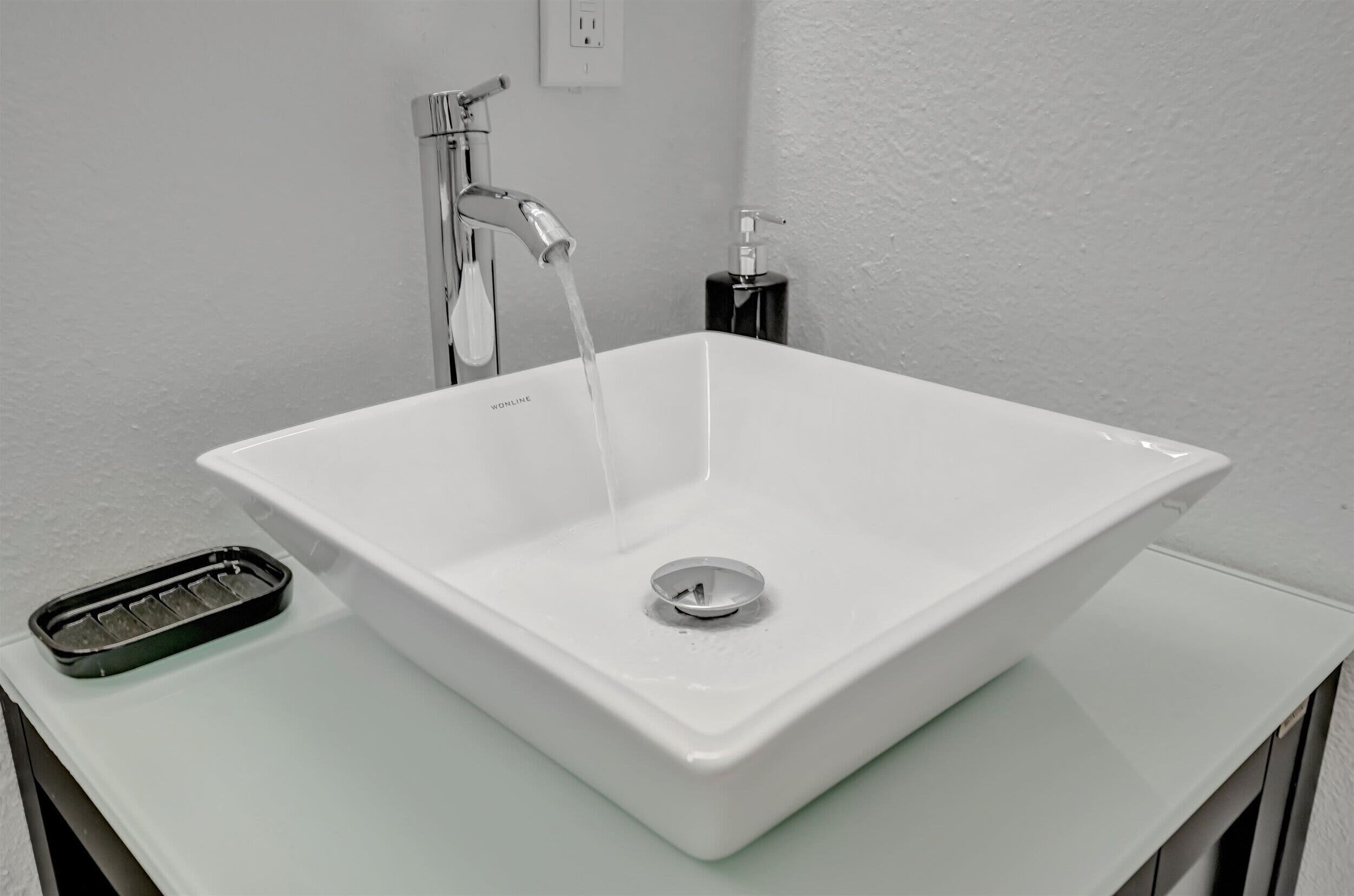 A white bathroom sink with a chrome faucet and a soap dispenser.