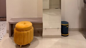 A modern bathroom with a large mirror, a yellow ottoman, and a trash bin. - Aesthetic 1bhk luxe Indore (Indore)