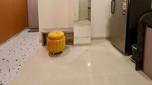 A modern kitchen with a refrigerator, a small yellow stool, and a tiled floor. - Aesthetic 1bhk luxe Indore (Indore)