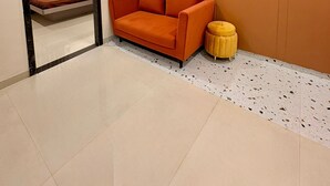 A modern room with a sofa, a small stool, and a mirror reflecting a bed with curtains. - Aesthetic 1bhk luxe Indore (Indore)