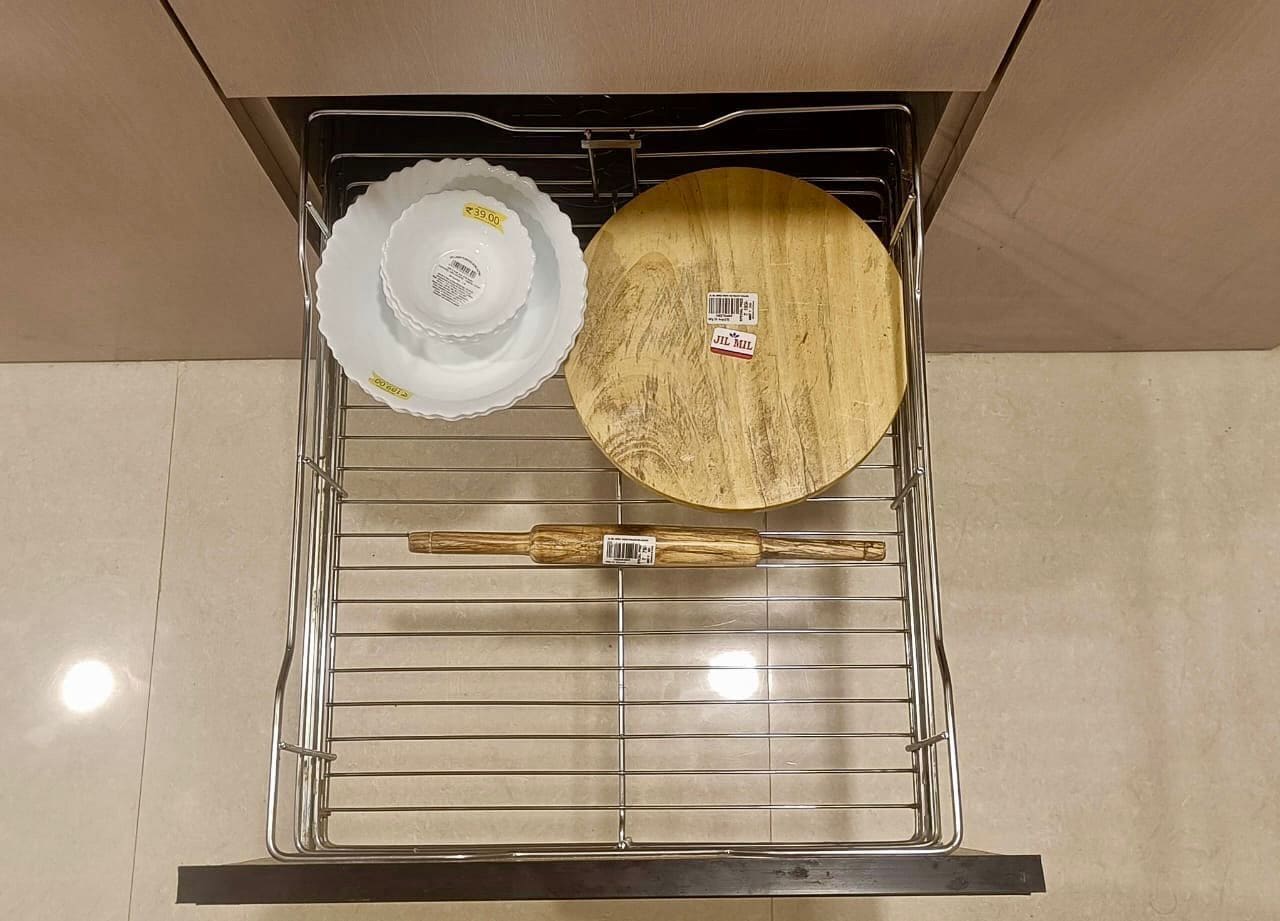 Una cocina con un estante metálico que sostiene un plato blanco, un cuenco de madera y una cuchara de madera.