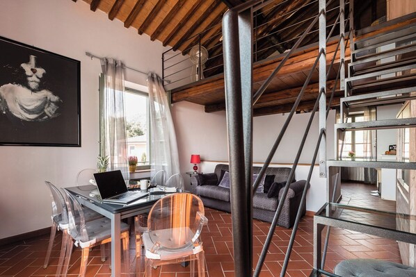 A modern living space with a dining area, a sofa, and a staircase.
