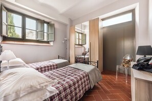 A bedroom with two beds, a desk, a chair, a lamp, and a wardrobe.