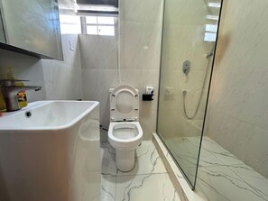 A bathroom with a white sink, toilet, and glass-enclosed shower. - BUYUN HOTEL (Abuja)