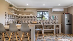 Une cuisine moderne dotée d’un îlot central, de tabourets de bar, d’un four encastré et d’un réfrigérateur en acier inoxydable.