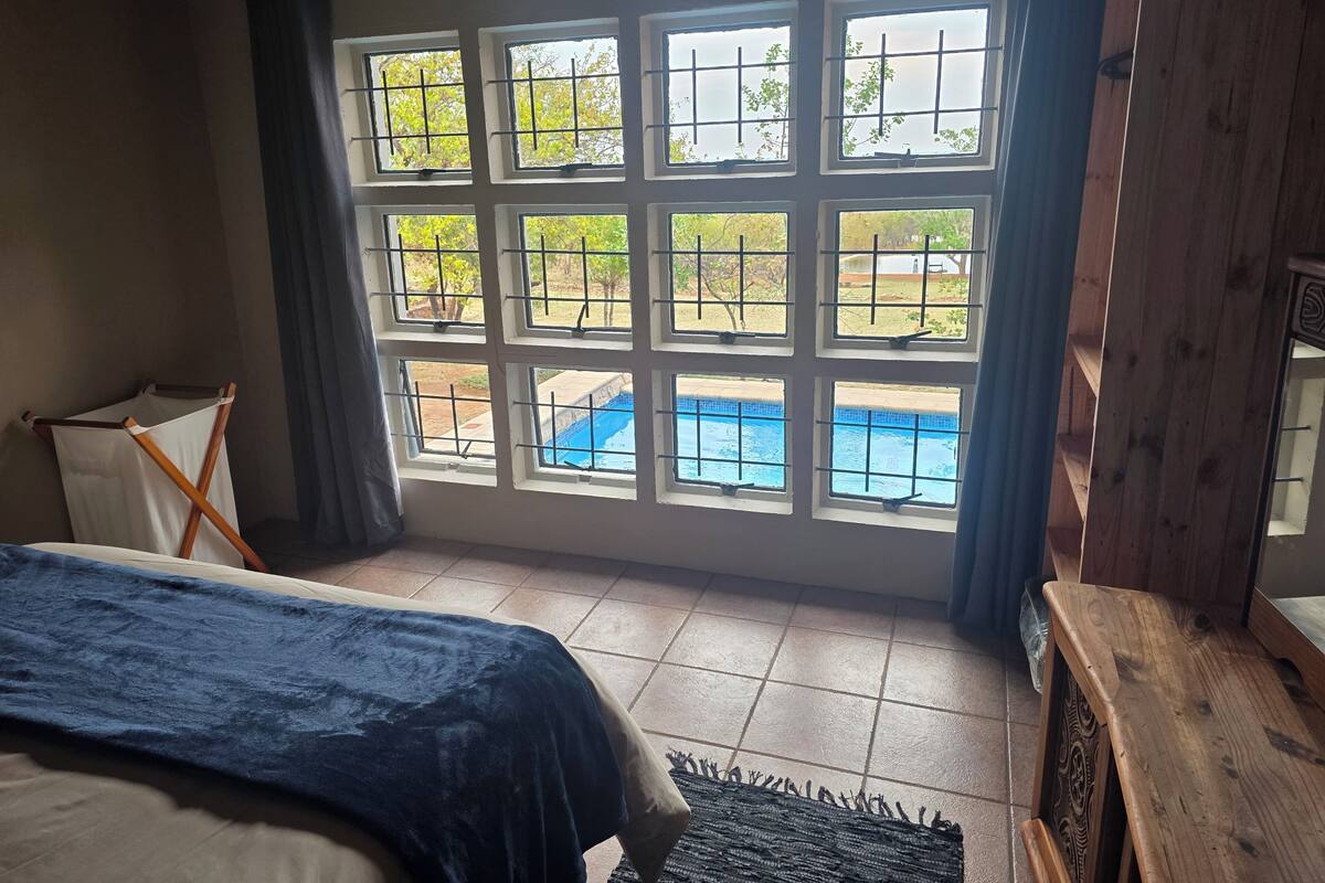 Ein Schlafzimmer mit großem Fenster und Blick auf einen Swimmingpool.