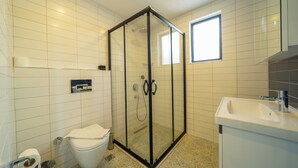 A bathroom with a glass-enclosed shower, a toilet, and a sink. - Bossa Nova Mare (Kas)
