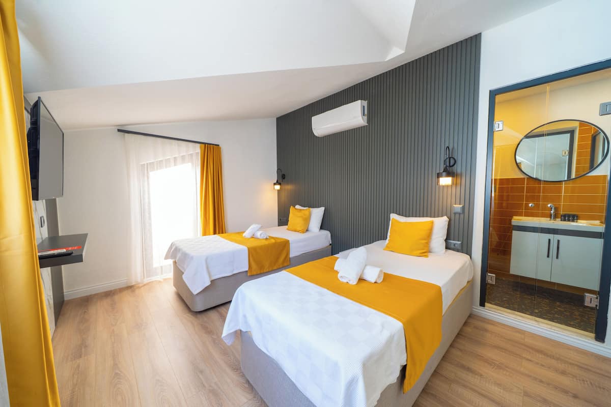 Habitación de hotel con dos camas, baño y televisor.