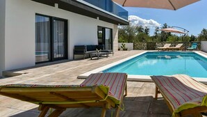 Een modern zwembadgedeelte met ligbedden en een terras.