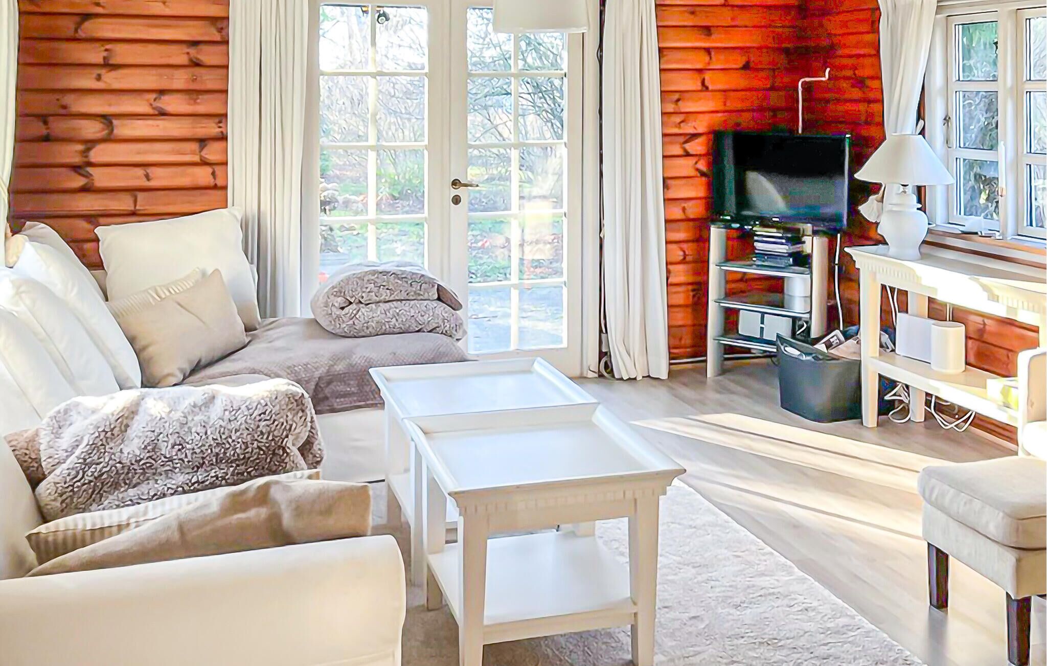 Ett mysigt vardagsrum med en soffa, ett soffbord, en tv och ett litet bord med en lampa.