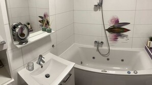 A bathroom with a bathtub, a sink, a shower, and a mirror. - Cozy Corner Ljubljana - Modern Urban Retreat (Ljubljana)