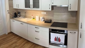 A modern kitchen with white cabinets, a wooden countertop, a built-in oven, and a coffee machine. - Cozy Corner Ljubljana - Modern Urban Retreat (Ljubljana)