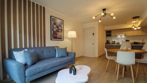 Una sala de estar moderna con un sofá gris, una mesa de centro blanca y un comedor con una mesa y sillas de madera.