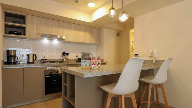 Una cocina moderna con armarios de madera, horno empotrado, cafetera y una barra con taburetes.