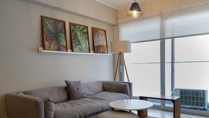 A modern living room with a sofa, a round coffee table, and a floor lamp. There are three framed artworks on the wall above the sofa. - w Comfortable 2BR w Balcony in Miraflores (Lima)