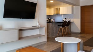 A modern living room with a flat-screen TV, a wooden coffee table, and a kitchen area with a bar and stools. - w Comfortable 2BR w Balcony in Miraflores (Lima)