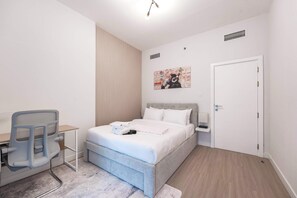 Ein Schlafzimmer mit Bett, Schreibtisch, Stuhl und einer Tür.