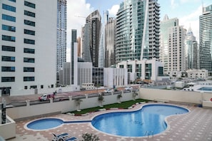 Ein modernes Hotel mit Pool auf dem Dach, umgeben von hohen Gebäuden.