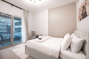 Ein modernes Schlafzimmer mit einem großen Bett, einem Schreibtisch und Blick auf einen Balkon.