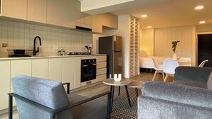 A modern kitchen with white cabinets, a black refrigerator, and a stove. There is a dining area with a small table and two chairs. - w Enchanting Loft w Balcony in Barranco (Lima)