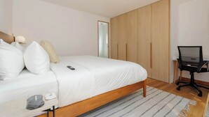 Een slaapkamer met een bed, bureau en kledingkast.
