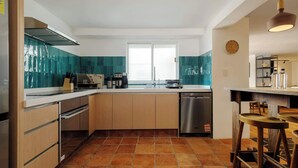 Een moderne keuken met een centraal eiland, roestvrijstalen apparatuur en een groot raam dat voor natuurlijk licht zorgt.