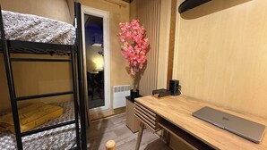 A bunk bed with a white blanket, a desk with a laptop, a pink artificial plant, and a radiator. - Chalet Prestige - Oasis Village 5 stars - Comfort and calm (Puget-sur-Argents)