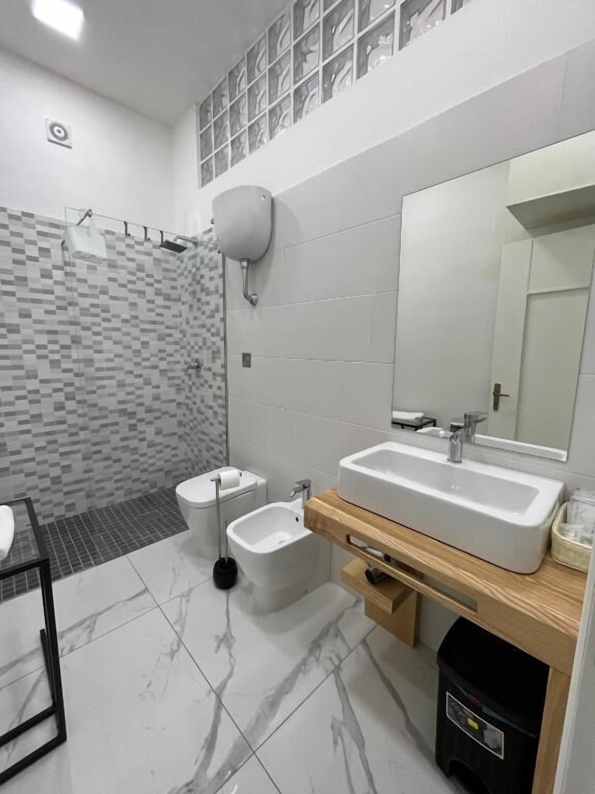 Ein modernes Badezimmer mit einem großen Spiegel, zwei Waschbecken, einer Toilette und einem Bidet.