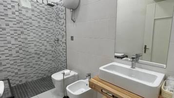 Ein modernes Badezimmer mit einem großen Spiegel, zwei Waschbecken, einer Toilette und einem Bidet.