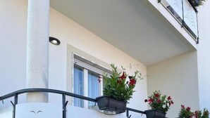 Ein Balkon mit weißer Brüstung, Pflanzkübeln und einer Steinmauer.