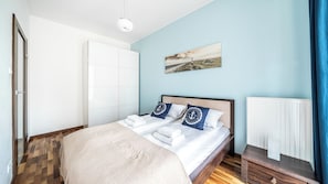 Un dormitorio con una cama, un radiador, un cuadro y suelo de madera.