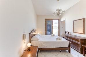 A bedroom with a bed, bedside table, lamp, wooden dresser, and a mirror. - Apartment 'Rocco 1' with Air Conditioning (Torre San Giovanni)