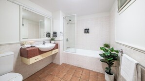 Une salle de bain équipée de toilettes, d’un lavabo, d’un miroir, d’une douche et d’une plante en pot.
