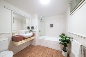 A bathroom with a toilet, sink, mirror, shower, and a potted plant. - Infinite Blue (Airlie Beach)