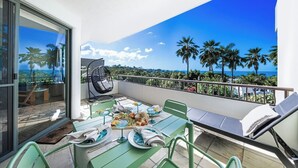 Un balcon avec une table à manger pour deux personnes, une chaise et un fauteuil de relaxation.