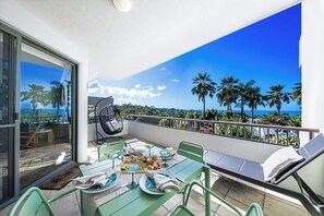 A balcony with a dining table set for two, a chair, and a sun lounger. - Infinite Blue (Airlie Beach)