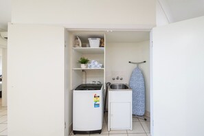 Eine kleine Küchenzeile mit kleinem Kühlschrank, Spüle und einem Wäscheständer.