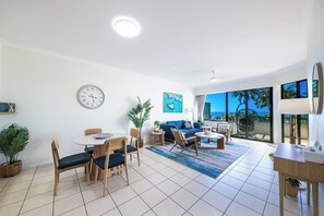 Ein modernes Wohnzimmer mit Essbereich, einem großen Fenster und Blick sowie einer Uhr an der Wand.