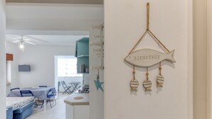 A modern interior with a dining area, kitchenette, and a 'BIENVENUE' sign.