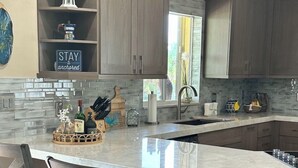 Una cucina moderna con isola centrale, sgabelli da bar e mobili a incasso.