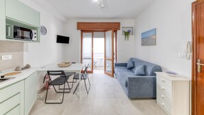 Een ruimtelijke leefruimte met een kitchenette, eethoek en een bank.