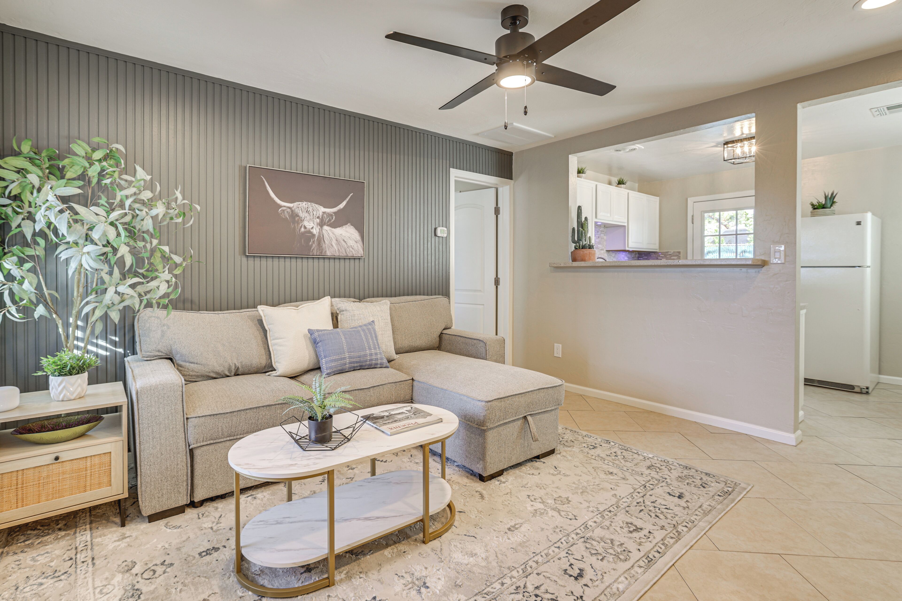 A modern living room with a sectional sofa, a round coffee table, and a large plant.