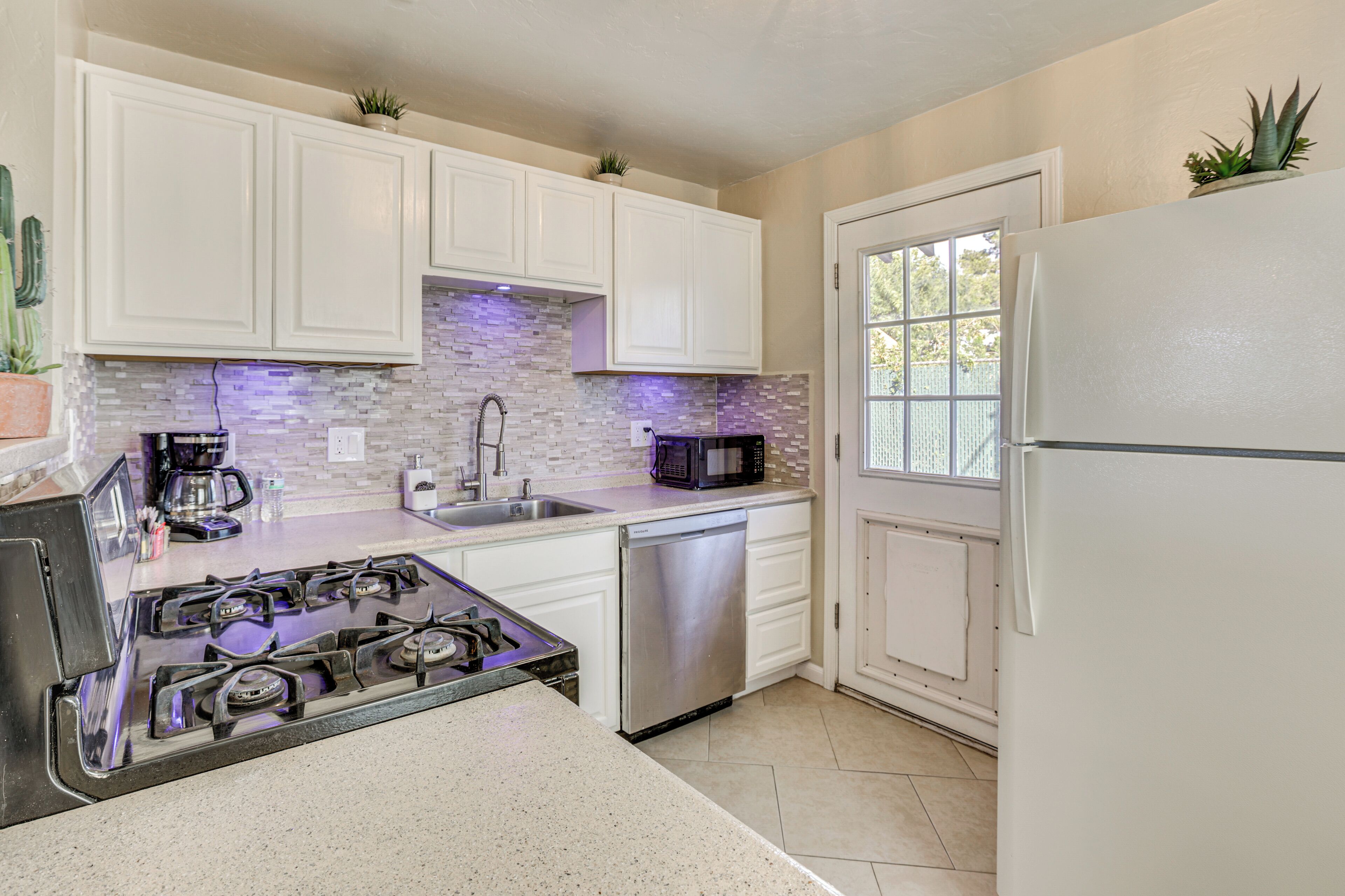 A kitchen with white cabinets, a stainless steel dishwasher, a gas stove, and a refrigerator.