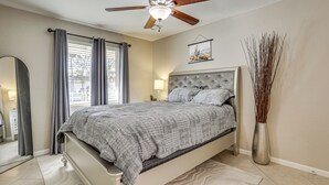 A bedroom with a bed, a ceiling fan, a window with curtains, a bedside lamp, a vase with branches, and a framed picture on the wall. - 4 Mi to Dtwn Phx: Midtown Condo w/ Patio! (Phoenix)