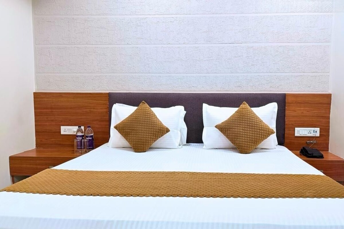 A neatly made bed with a white and brown bedspread, two pillows, and a wooden headboard.
