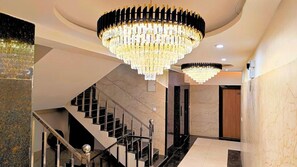 A grand staircase with a chandelier, marble walls, and a modern interior design. - White Panda Hotels Royal Inn (Haridwar)