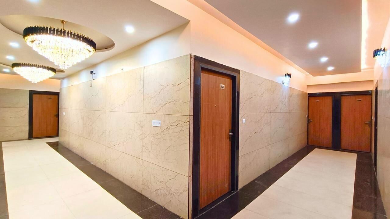 A hotel corridor with marble walls, wooden doors, and a chandelier.