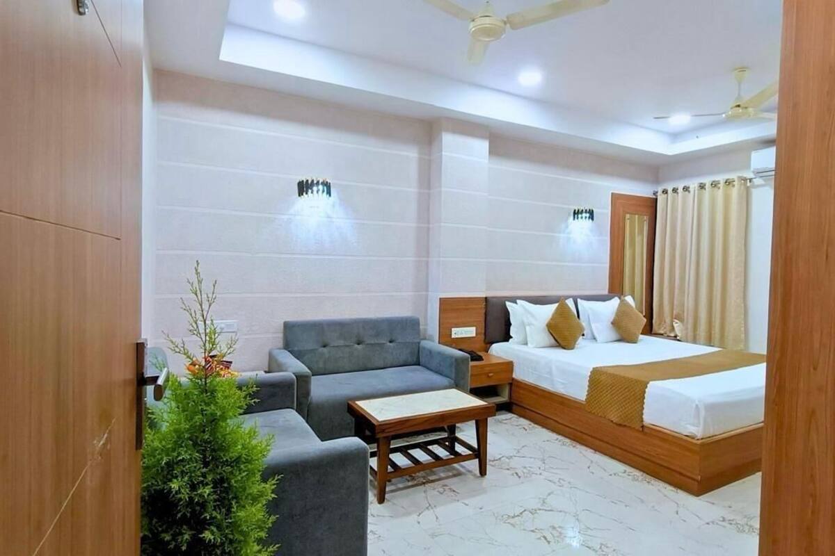 A hotel room with a bed, a sofa, a small table, and a nightstand.